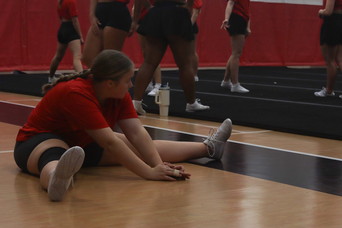 Sophia Soulis stretches while watching her teammates during cheer practice in Des Moines, Iowa on November 19, 2025