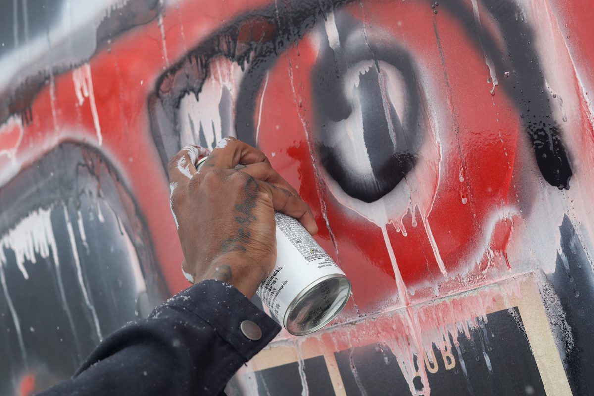 At the train tracks in Des Moines, Iowa Jordan spray paints his name in black on Saturday, December 1st, 2025.