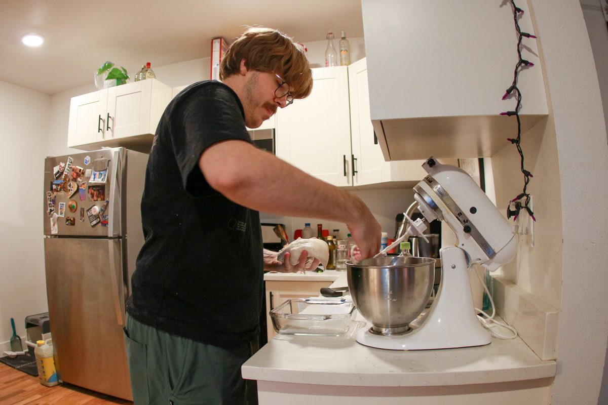 Milos Garton sticks his tongue out in concentration as he grabs the dough from the mixer in his studio apartment in Highland Park, Iowa on Wednesday, November 19, 2025.
