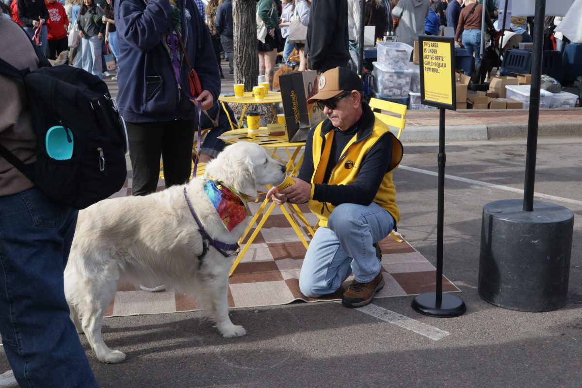 Man shares whip cream on his coffee with his golden near a coffee truck.